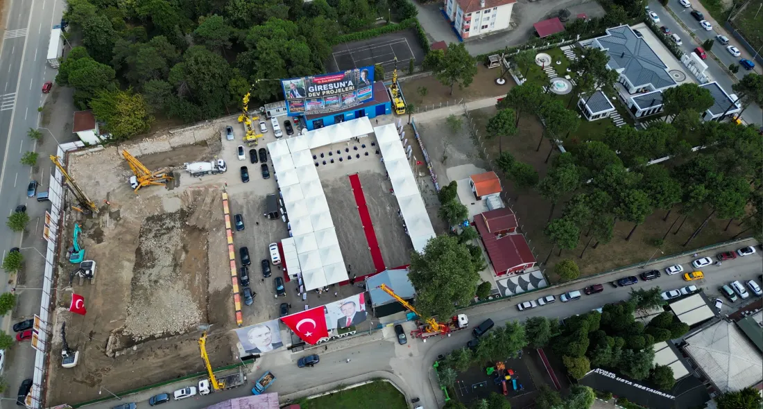 Şantiyenin havadan görünümü: kazısı yapılmış temel alanı, iş makineleri, yanında tören çadırları ve kırmızı halı