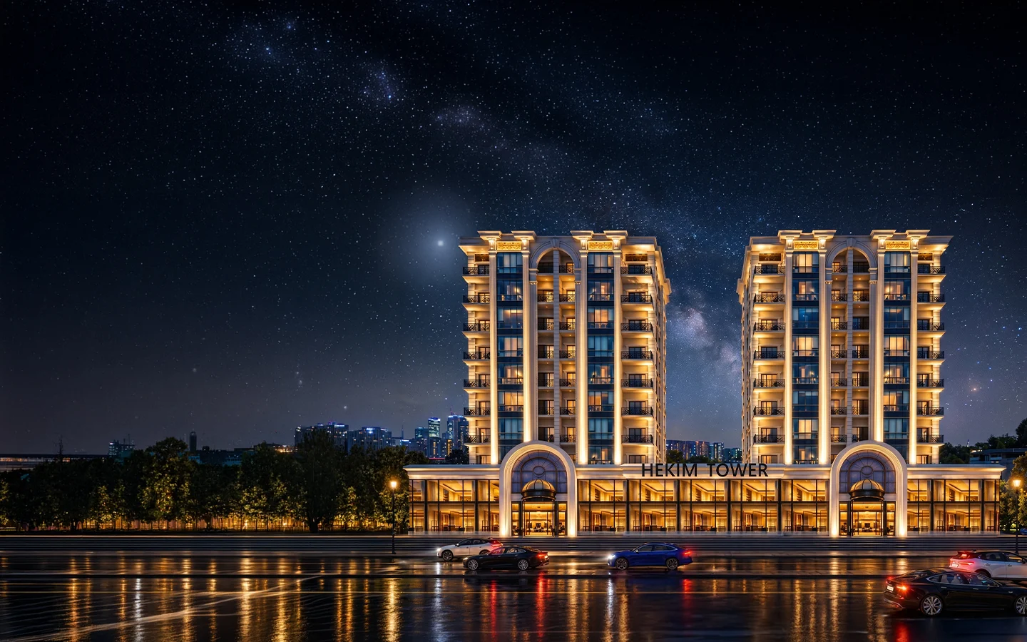 Hekim Tower gece görünümü: aydınlatılmış iki kule, zemin kattaki vitrinli ticari üniteler ve bulvar